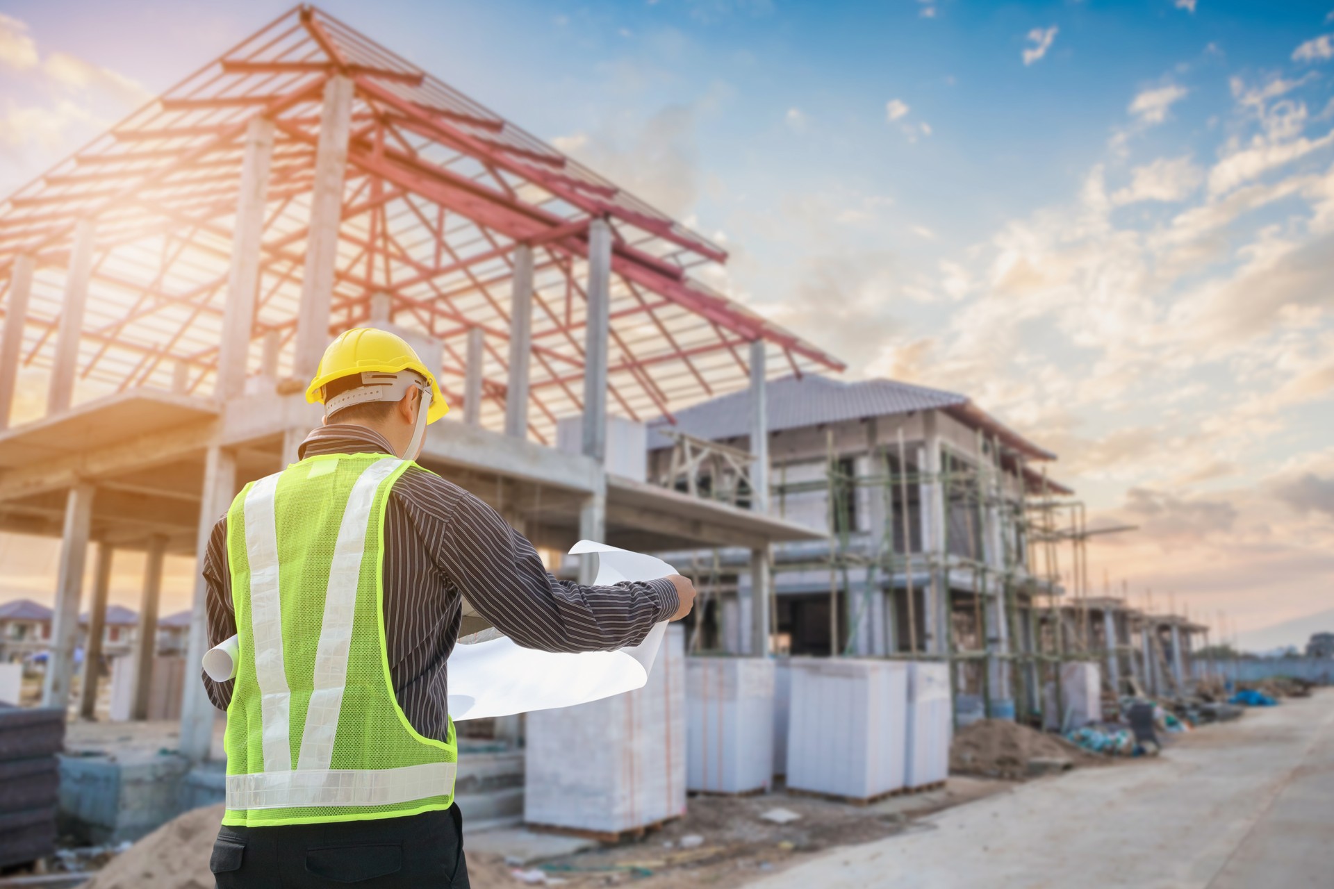 Professional engineer architect worker with protective helmet and blueprints paper at house building construction site